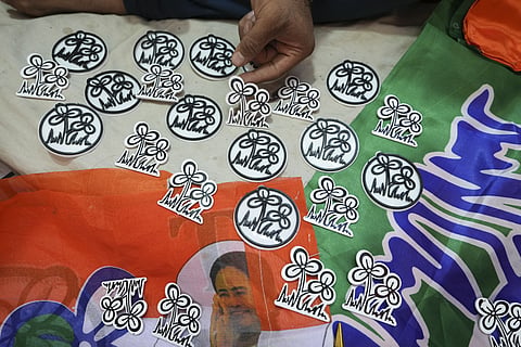 A shopkeeper shows stickers with depictions of the TMC party logo at his shop, ahead of the West Bengal Assembly elections, in Kolkata. 