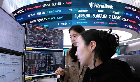 Currency traders watch monitors near a screen showing the Korea Composite Stock Price Index (KOSPI), top center, and the foreign exchange rate between U.S. dollar and South Korean won, top center left, at the foreign exchange dealing room of the Hana Bank headquarters in Seoul, South Korea, Tuesday, March 24, 2026. 