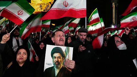 Pro-government supporters wave national flags as one of them holds a picture of the Supreme Leader Ayatollah Mojtaba Khamenei during a rally in a square in western Tehran, Iran, Wednesday, March 25, 2026. 
