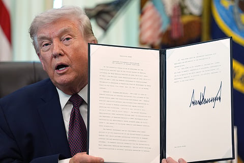 President Donald Trump holds a signed executive order in the Oval Office of the White House Tuesday, March 31, 2026, in Washington. 