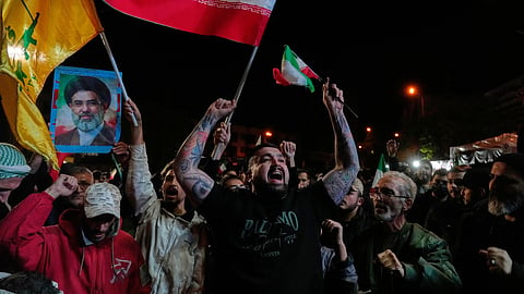 Demonstrators chant slogans as they hold Iranian flags and a poster of the Supreme Leader Ayatollah Mojtaba Khamenei in a gathering after the announcement of a two-week ceasefire in the war with the US and Israel at the Enqelab-e-Eslami, or Islamic Revolution, Square, in Tehran, Iran, Wednesday, April 8, 2026.