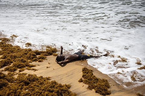 A visitor lies on the shore on the beach near the Door of No Return monument in Ouidah on April 6, 2026. 