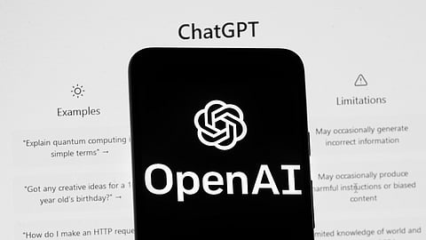 The OpenAI logo is seen on a mobile phone in front of a computer screen which displays the ChatGPT home Screen, March 17, 2023, in Boston.