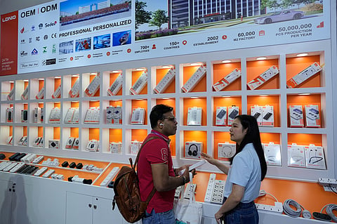 A vendor attends a foreign visitor at a booth showcasing electronic devices at the Canton Fair, in Guangzhou, in southern China's Guangdong province, Wednesday, April 15, 2026. 