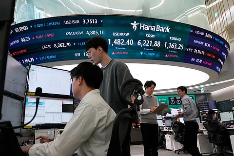 Currency traders work near a screen showing the Korea Composite Stock Price Index (KOSPI), top center, and the foreign exchange rate between U.S. dollar and South Korean won, top center left, at the foreign exchange dealing room of the Hana Bank headquarters, in Seoul, South Korea, Friday, April 17, 2026.