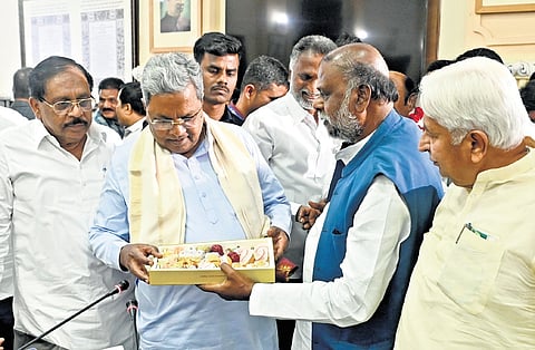 Former minister H Anjaneya distributes sweets to CM Siddaramaiah and ministers after the cabinet decided to implement 15% internal quota for Scheduled Castes, at Vidhana Soudha in Bengaluru on Friday  