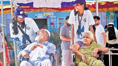 Hand of help:  Elderly voters share a light moment with volunteers at a polling station in Chennai.