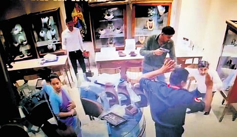 CCTV footage shows a shop employee holding up his hands as a robber brandishes a pistol.