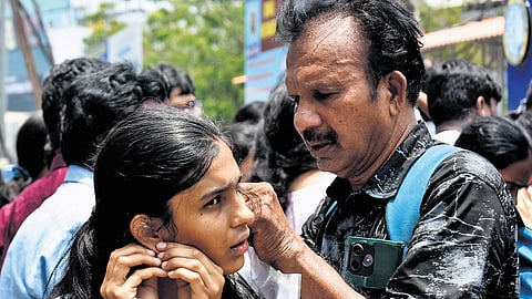 A parent helps her daughter in removing earrings before entering NEET centre in Vijayawada on Sunday.