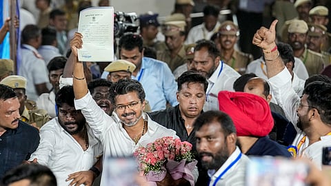 TVK chief and Tiruchirappalli East constituency candidate Vijay holds the certificate outside a counting centre as he leads in the polls, at Loyola College, in Chennai, Tamil Nadu, Monday, May 4, 2026. 