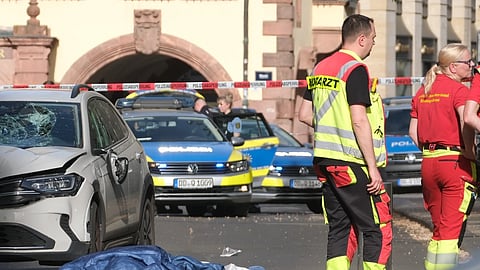 Rescue workers stand next to a damaged car that has crashed into several people in Leipzig, Germany, Monday, May 4, 2026.