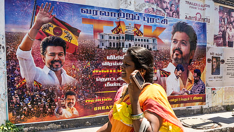 A woman walks past a banner of actor and Tamilaga Vettri Kazhagam (TVK) President Chandrasekaran Joseph Vijay, after his party surprisingly emerged as the single largest party in the April 23 polls to the Tamil Nadu state Assembly, in Chennai, Thursday, May 7, 2026. 