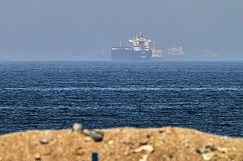 Cargo ships are seen at sea near the Strait of Hormuz, as viewed from a rocky shoreline near Khor Fakkan, United Arab Emirates, Friday, May 1, 2026.