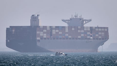 A container ship sits at anchor as a small motorboat passes in the foreground in the Strait of Hormuz off Bandar Abbas, Iran, Saturday, May 2, 2026. 