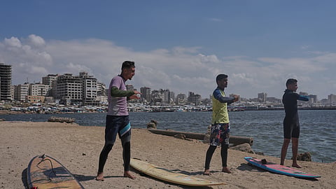 Palestinians Tahseen Abu Assi, left, Khalil Abu Jayyab, center, and Abed Rahim Alostaz warm up before surfing on the beach in Gaza City.