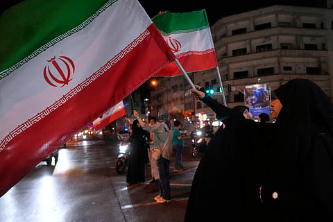 Women hold Iranian flags for a pro-government campaign in downtown Tehran, Iran, Friday, May 8, 2026.