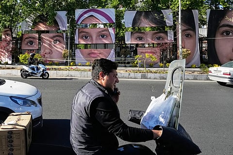 Vehicles drive past banners showing portraits of the school children who were killed during a strike on a school in southern town of Minab on Feb. 28, at Tajrish square in northern Tehran, Iran, Sunday, May 10, 2026.