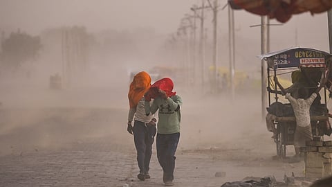 Commuters make their way through a dust storm in Prayagraj, Uttar Pradesh, on Wednesday, May 13, 2026.