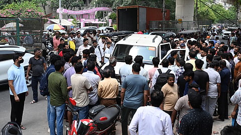 People gather near closed and walled-up commercial establishments ahead of sealing drive by Municipal Corporation at New Ashok Nagar, in New Delhi on Tuesday. Local shop owners have reportedly shut their businesses.