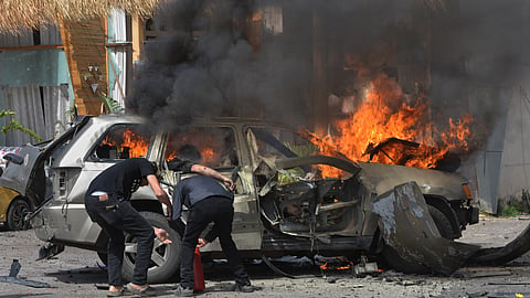 A person is seen inside a burning vehicle as men attempt to put out the fire after an Israeli airstrike hit a car in the coastal town of Barja, south of Beirut, Lebanon, Wednesday, May 13, 2026.