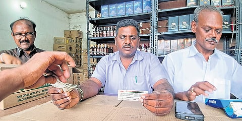 Employee verifying the age of a customer at a liquor outlet in Chennai.