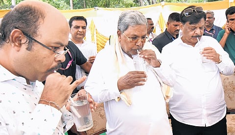 Chief Minister Siddaramaiah, Social Welfare Minister HC Mahadevappa and MLC Yathindra Siddaramaiah sip tender coconut water to beat the heat during an inspection spree in Mysuru on Thursday.