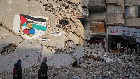 Women and children walk past a mural depicting FC Barcelona football player Lamine Yamal holding a Palestinian flag on the rubble of a destroyed building in northern Gaza City, Thursday, May 14, 2026. 