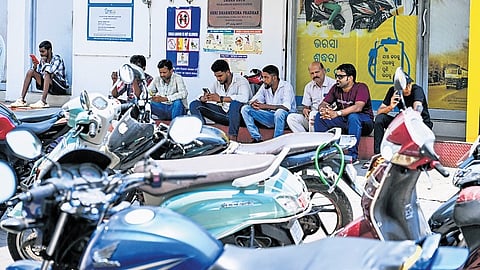 People waiting in shade while leaving their two-wheelers in scorching heat while waiting for fuel at a petrol pump near Unit 2 in Bhubaneswar.