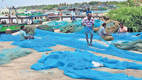 Fishermen mending nets during the annual ban on a sunny Sunday morning at Rameswaram in Ramanathapuram district 