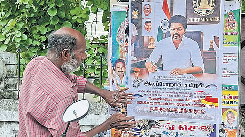 RM Sekar pastes a poster congratulating Chief Minister C Joseph Vijay on his election victory.