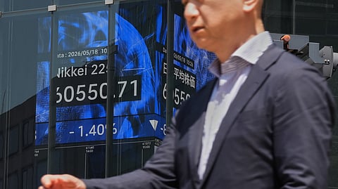 A person walks in front of an electronic board at a business building showing Japan's Nikkei index, Monday, May 18, 2026, in Tokyo.
