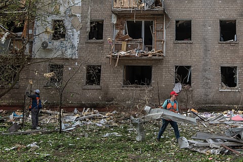 Communal workers clean debris in the courtyard of a damaged residential building following an air attack in Dnipro on May 18, 2026, amid the Russian invasion of Ukraine.