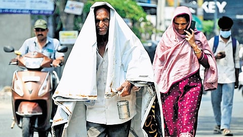 A man shields himself from the scorching sun with the help of a 
flex banner in Karimnagar on Wednesday.