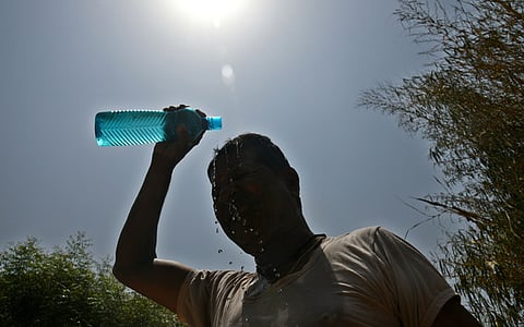 A man pours water over his head to beat the scorching heat as temperatures soar during the ongoing heatwave