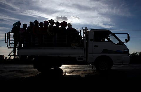 Garment factory workers ride a truck as they go home after a day's work at outside Phnom Penh, Cambodia. 