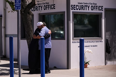 People embrace outside the security office of the Islamic Center of San Diego, a day after a shooting, Tuesday, May 19, 2026, in San Diego.