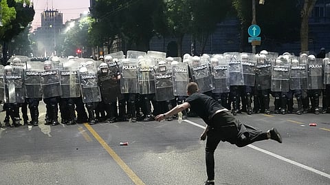 A man throws a cobblestone at riot police as clashes break out during a rally led by Serbia's protesting university students who are pushing for major political changes in the Balkan country run by President Aleksandar Vucic, in Belgrade, Serbia, Saturday, May. 23, 2026. 