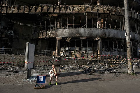 A boy plays the accordion in front of a shopping center damaged by Russian strikes in Kyiv on May 25, 2026, amid the Russian invasion of Ukraine. 