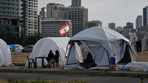 Displaced people who fled Israeli strikes in southern Lebanon sit outside shelter tents in Beirut, April 24, 2026.