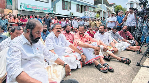 CPM leaders V Sivankutty and M V Govindan along with Rajya Sabha MP John Brittas stage a sit-in in front of Pinarayi’s house near Bakery Junction 