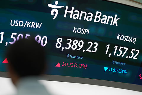 A dealer walks past near the screens showing the Korea Composite Stock Price Index (KOSPI) and the foreign exchange rate between U.S. dollar and South Korean won at a dealing room of Hana Bank in Seoul, South Korea, Wednesday, May 27, 2026.