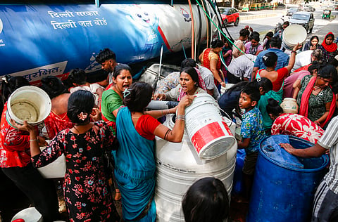 People gather around a water tanker to fill their empty containers amid scorching summer heat, in New Delhi, Wednesday, May 27, 2026. 
