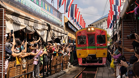A crowd of tourists take pictures of a passing train at the Mae Klong Railway Market near Bangkok, Thailand on Dec. 6, 2025. 