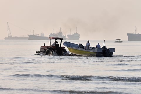 A tractor tows a small boat through shallow water as cargo ships and industrial vessels are anchored in the Strait of Hormuz off Bandar Abbas, Iran, Monday, June 1, 2026. 