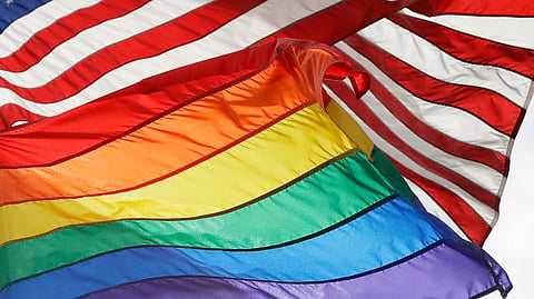 An LGBTQ+ pride flag flies beneath a US flag at the Stonewall National Monument in New York, on Oct. 11, 2017. 