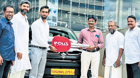 Chemnad West GUPS headmaster P T Benny (third from right) receiving the keys to the new car at the showroom as his retirement gift