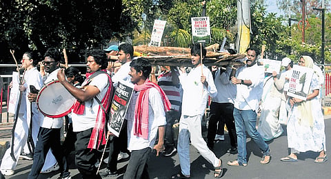 Residents carry tree trunks in a symbolic funeral procession near KBR Park to mark World Environment Day in Hyderabad on Friday. 
