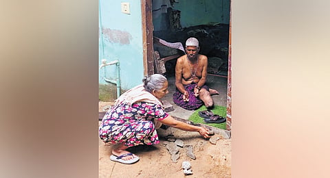 Rosy building a makeshift barrier of sand, stones and wooden planks at the entrance of her home in a desperate effort to keep out floodwaters at Balan Nagar near Poonthura, Thiruvananthapuram.