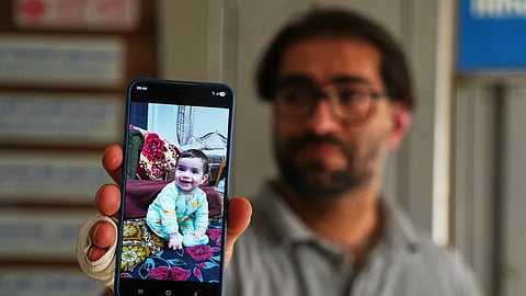 Fahd Abu Haikal, 41 displays a mobile photo of his seven month old Palestinian boy Sam, who was killed on Friday when Israeli soldiers fired at the vehicle carrying him and his parents, in Tel Rumeida, at a hospital in the West Bank city of Hebron Saturday, June 6, 2026.