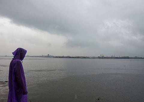A man covers himself during rainfall as monsoon arrives, at Marine Drive, in Kochi, Kerala, Friday, June 5, 2026. Heavy rains continued to lash several parts of Kerala, waterlogging roads and flooding low-lying areas, with the IMD on Friday issuing an orange alert in seven districts of the state.